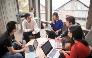 business economics students sitting around a round table with laptops