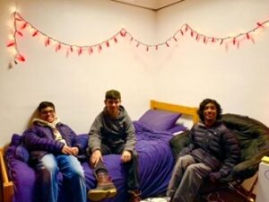 Adam Jamal '22 with two friends sitting in a college dorm room