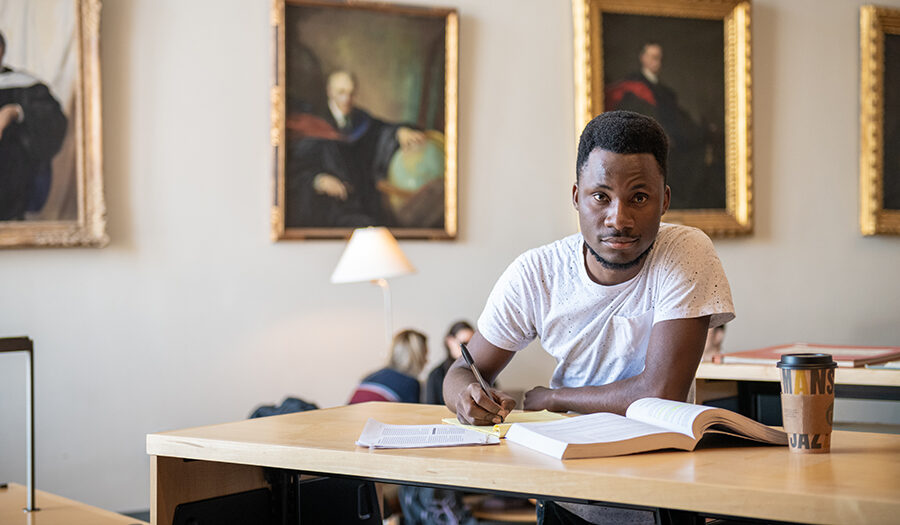 Emanuael, student writing notes in library