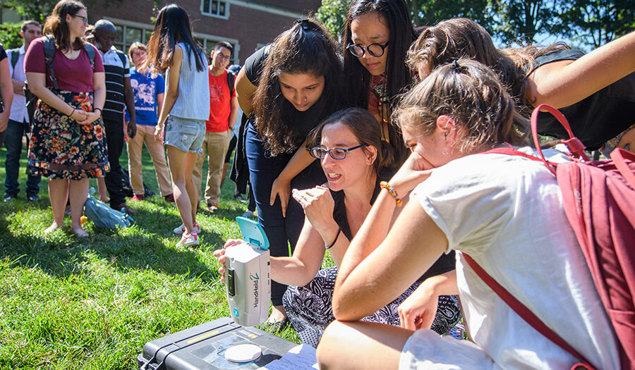 Professor Florencia with students looking at equip