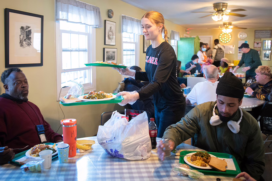volunteer handing food to gentlemen