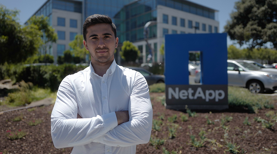 netApp student standing in fron tof sign