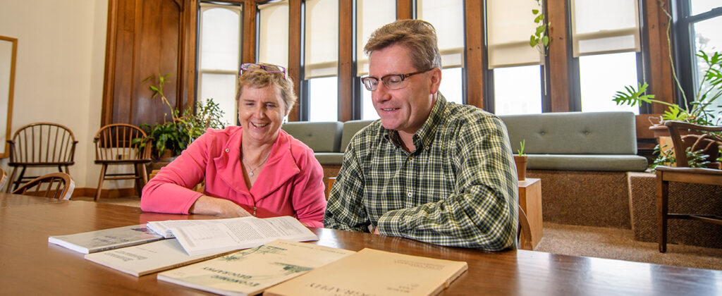 two professors in English house looking over books