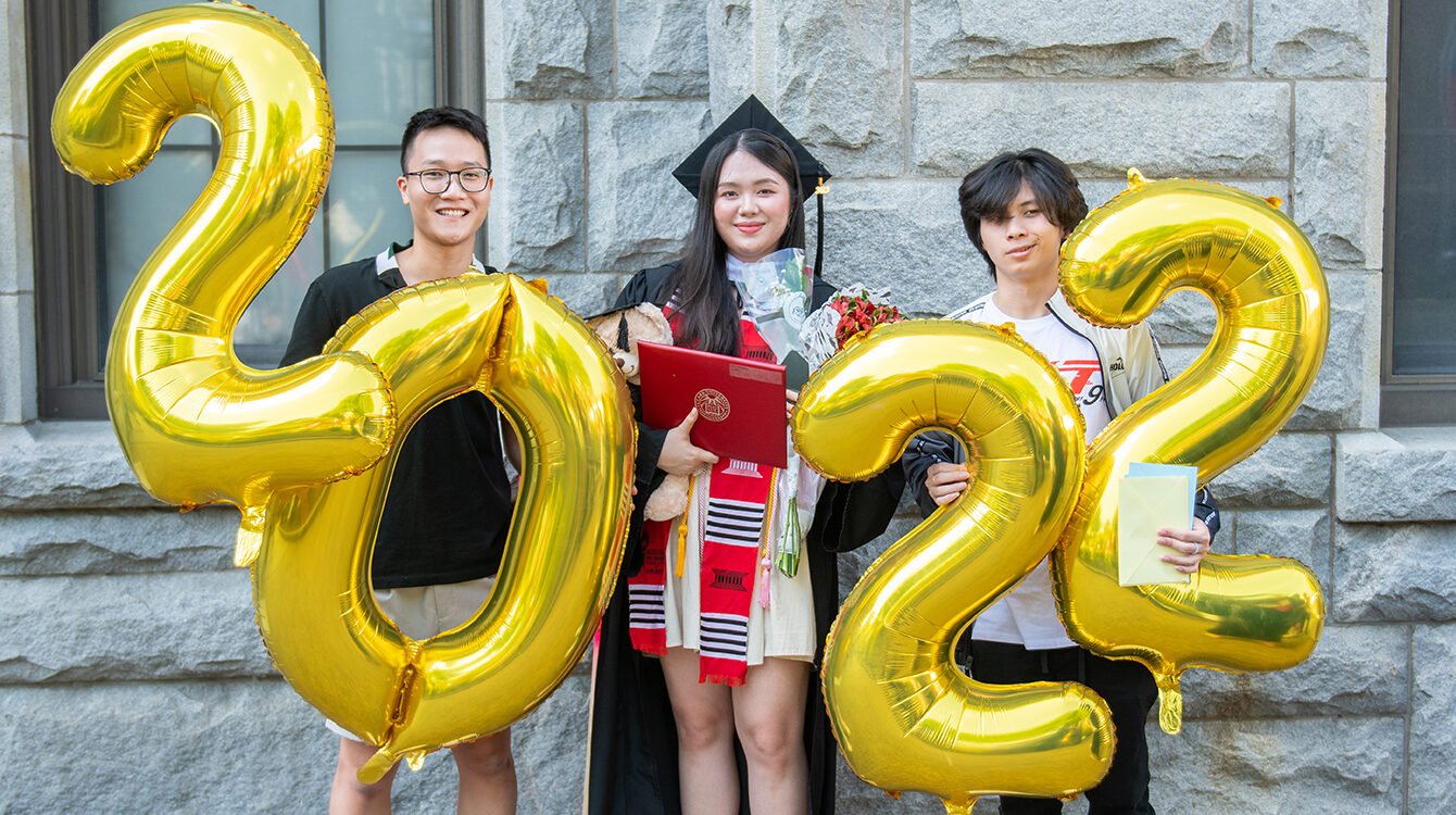 commencement 2022 - graduates holding up ballons and diploma