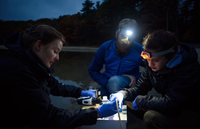 professor with students i field with head spot lights on