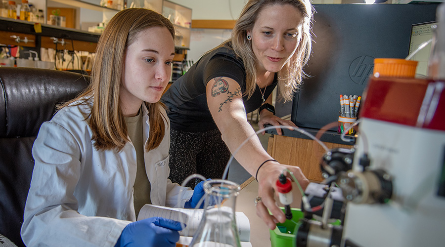 biochemistry student and faculty member in lab looking over equipment