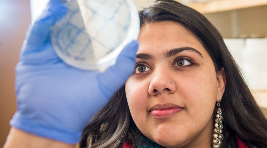 female student holding up a Petra dish in lab