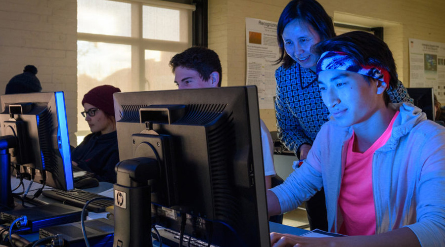 computer science professor overlooking student in front of computer screen