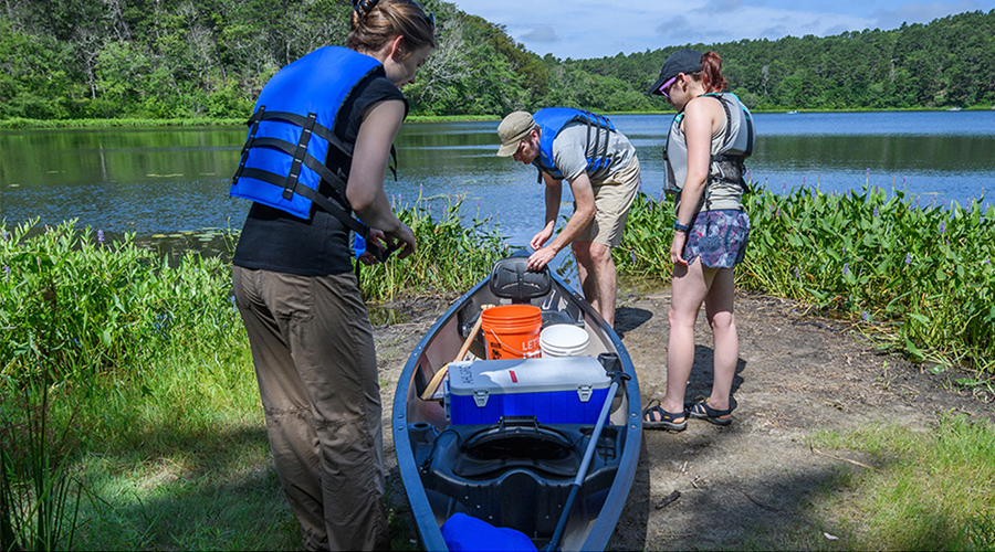 students going into canoe into a pond to take samples