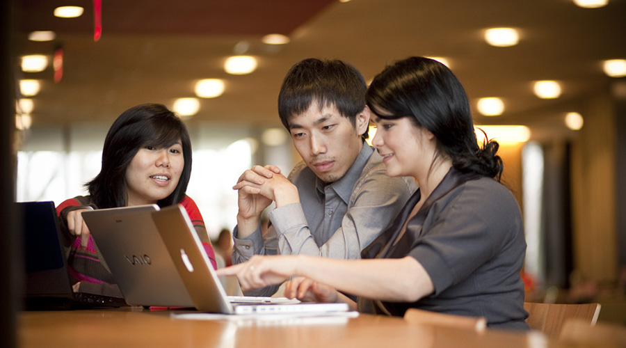 management students looking over computer