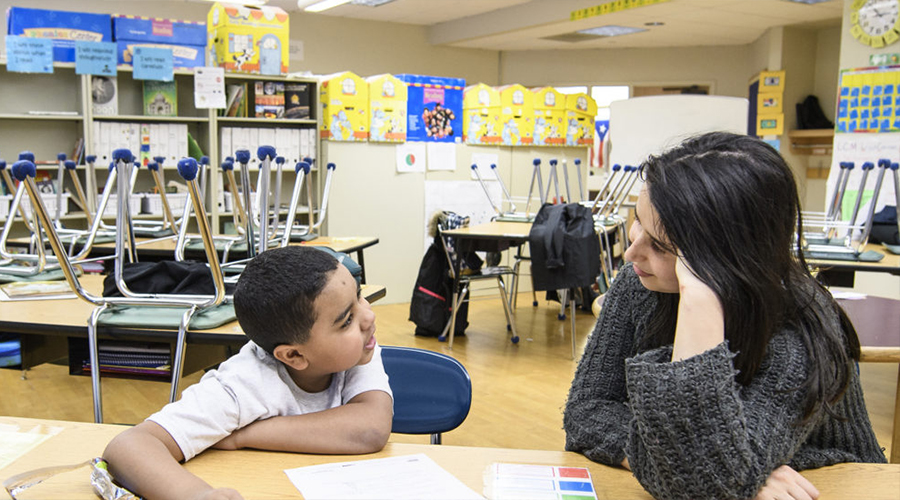 female student working with youth child at desk in teaching program