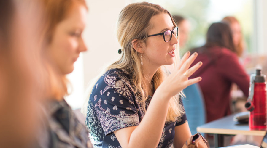 Psychology students sitting around table in class in discussions.