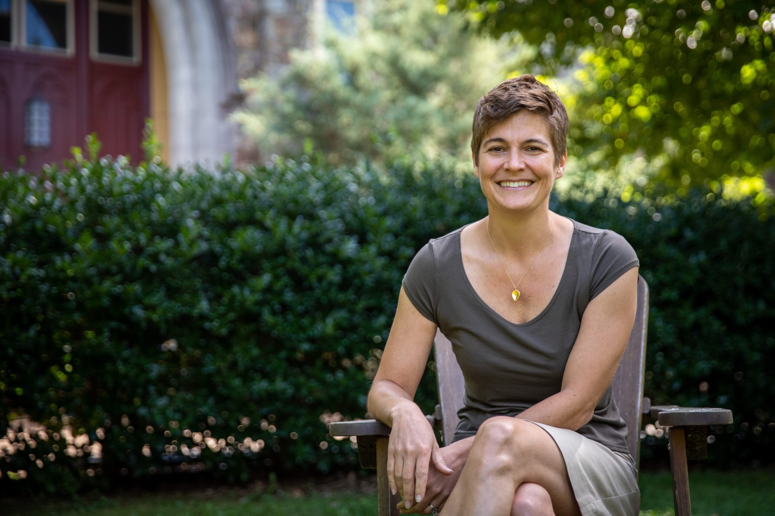 woman in gray shirt sitting on chair in front of greenery