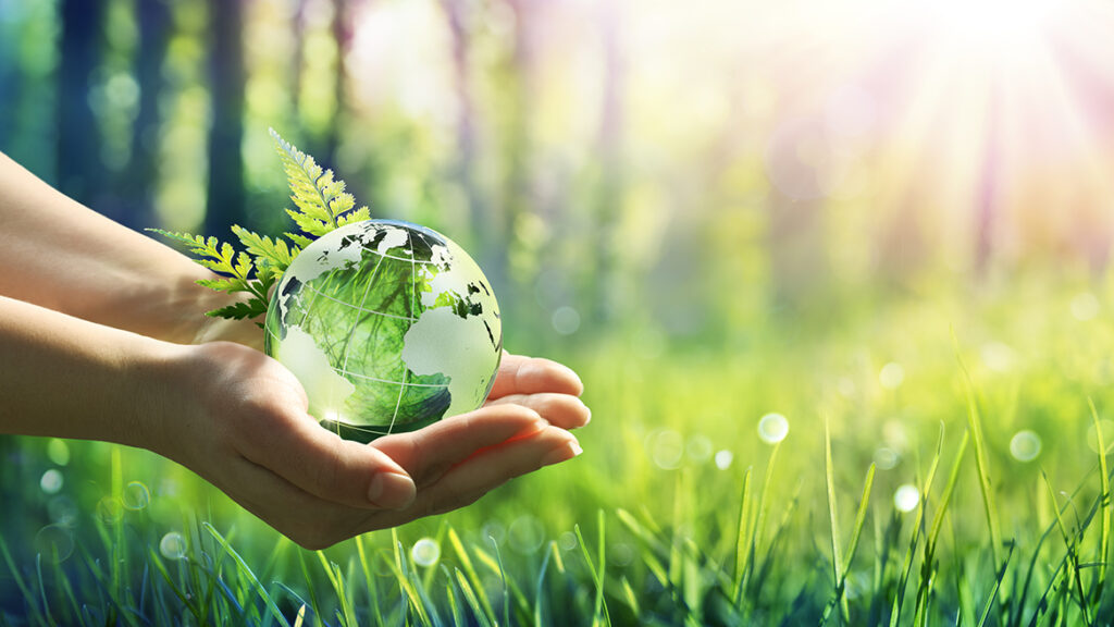 Hands holding a globe with a field in the background.