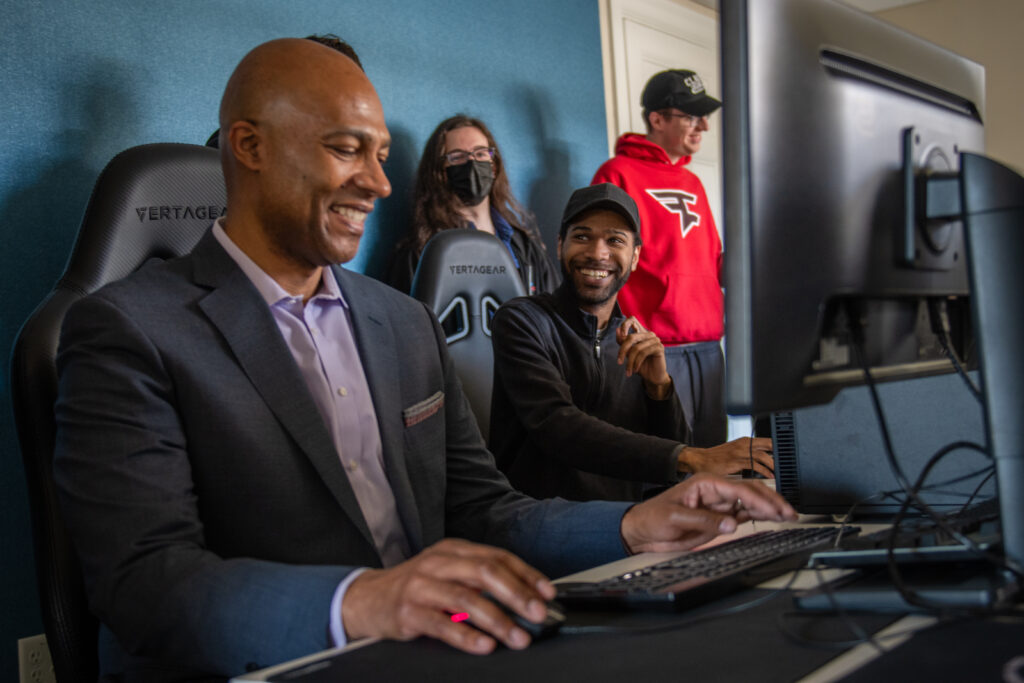 man plays computer game with students looking on