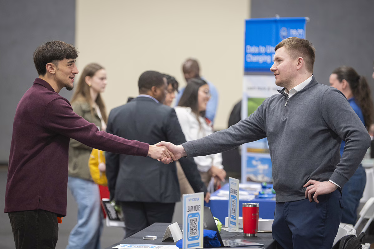 Student shaking hands with business person during career fair