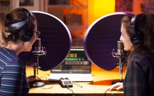 Multi Media students behind mics in recording studio doing a podcast