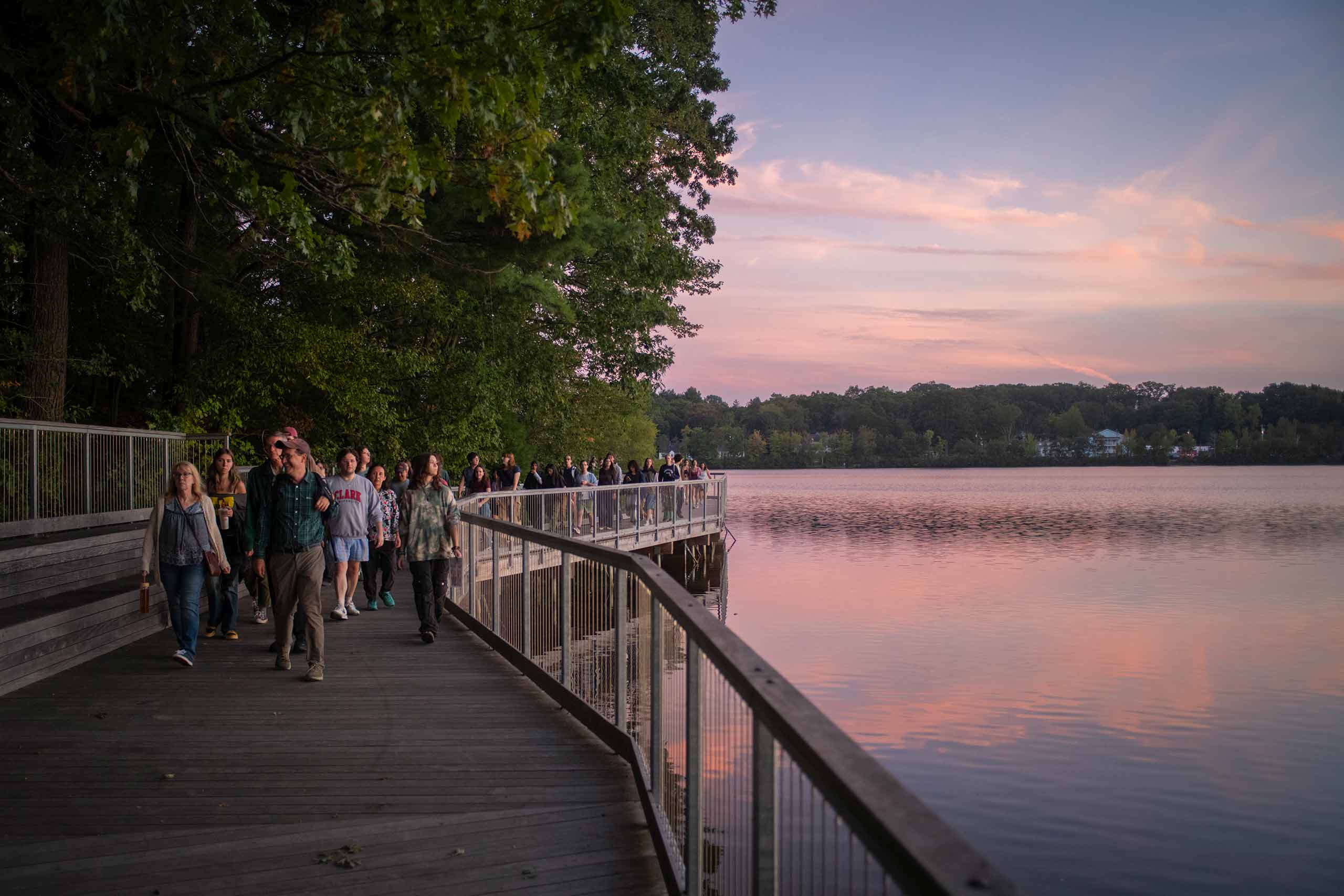 Students gathering on a boardwalk beside Coes reservoir at sunset