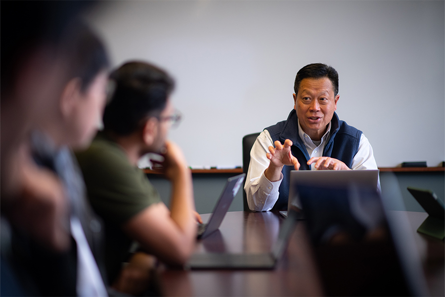 Professor lecturing graduate students at conference table