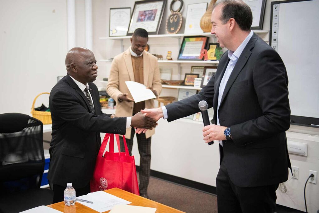Leaders from Clark University and African Community Education (ACE), a Worcester agency that works to help African refugee and immigrant youth and families achieve educational and social stability shake hands at a ceremony marking their collaboration.