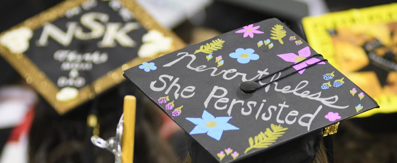 The top of a graduation cap with the words, "Nevertheless, she persisted."