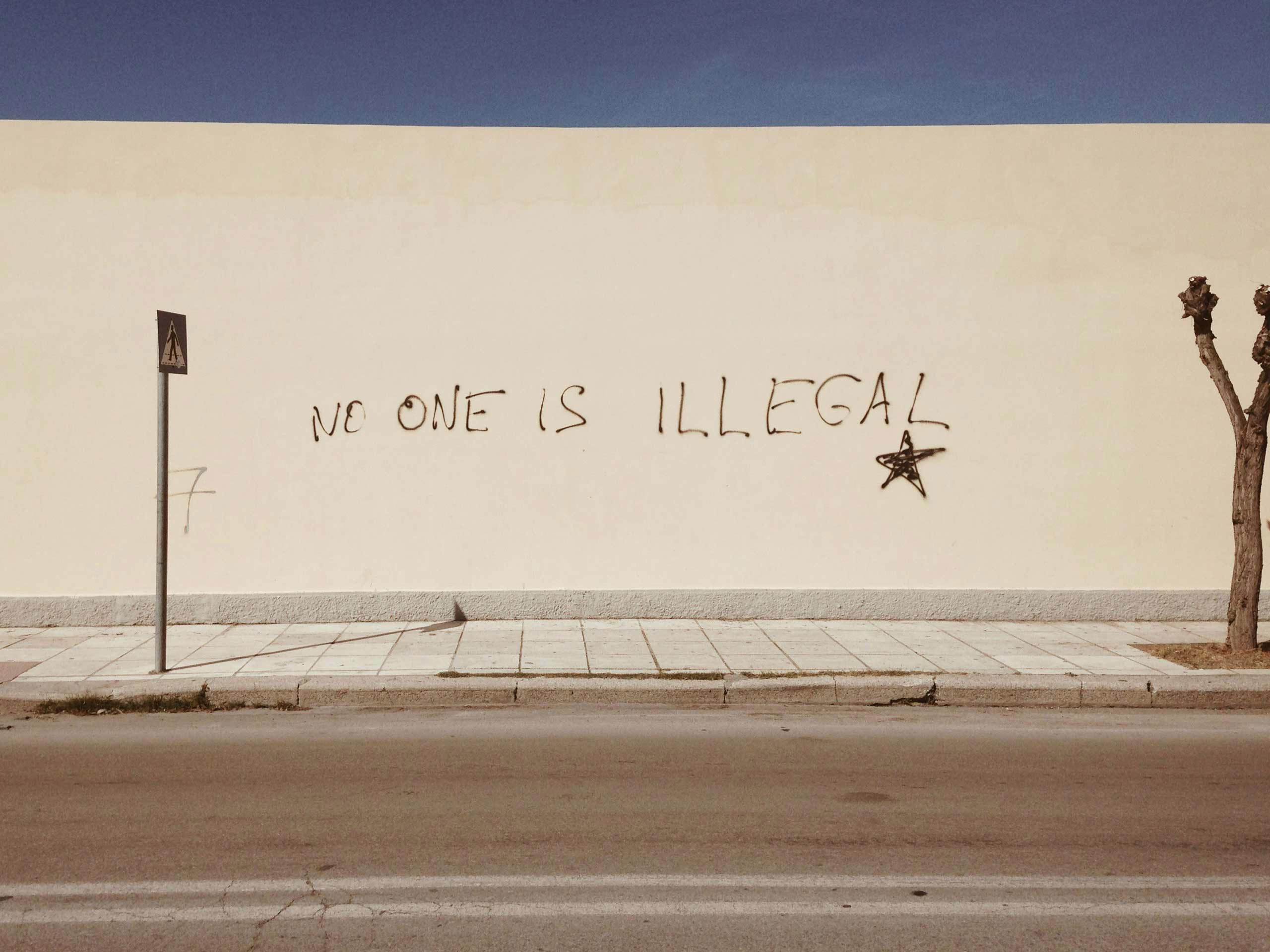 A wall with 'no one is illegal' written on it.