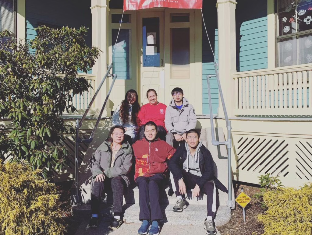 international students sitting on stairs of ISSO house with staff member