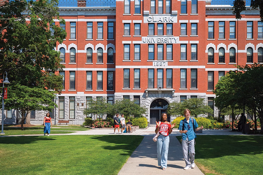 Two students walking side by side in front of Jonas Clark Hall