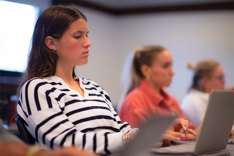 Graduate student taking notes on her laptop in classroom setting