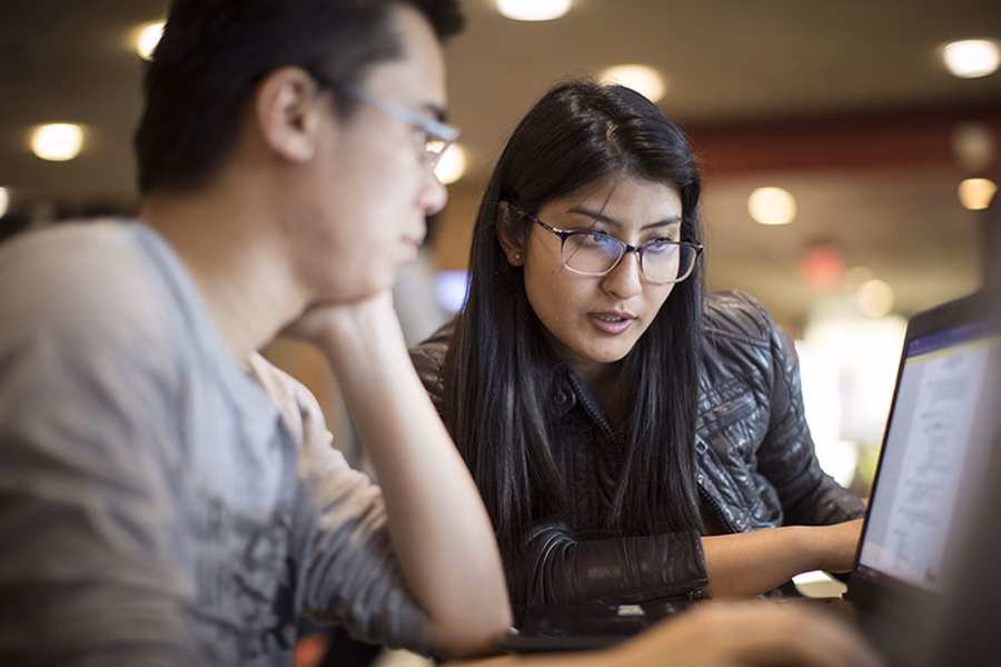 Student assisting another student with laptop