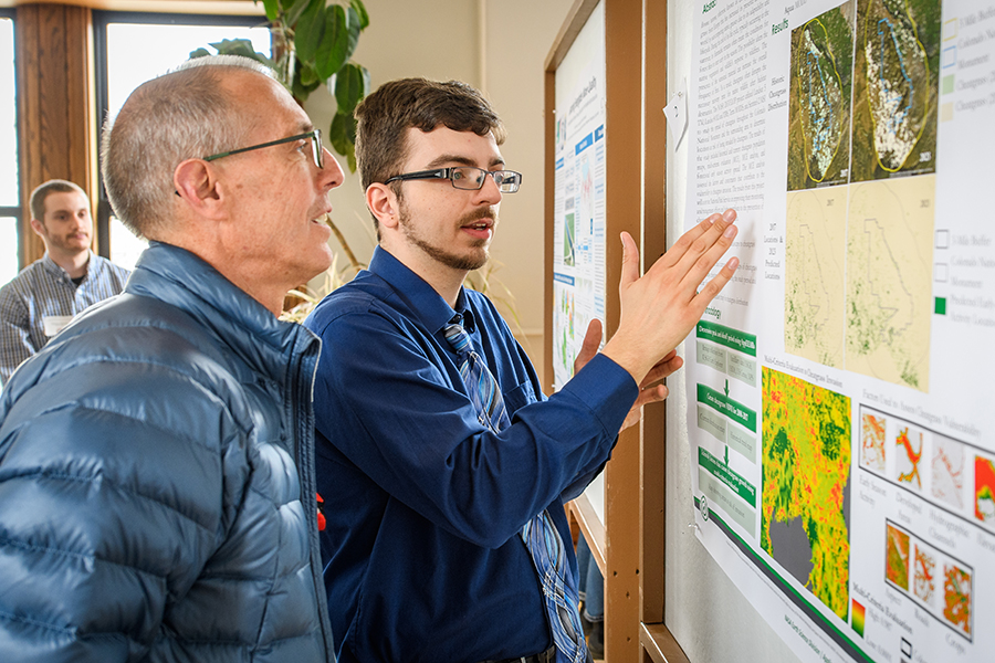 graduate student showing professor his research work at conference