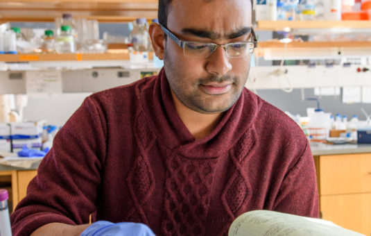 graduate student looking over bok in lab