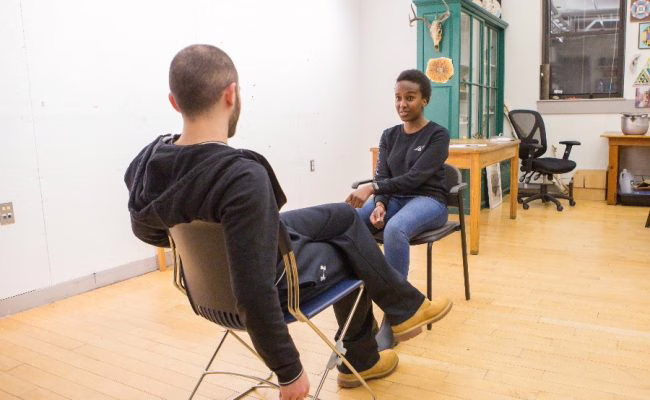 two students in chairs talking facing each other