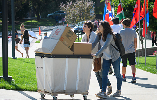 girls and mom pushing cart up to hall
