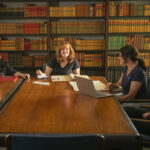 Four people sit at table in the library