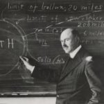 Robert Goddard posing in front of a chalk board with his work
