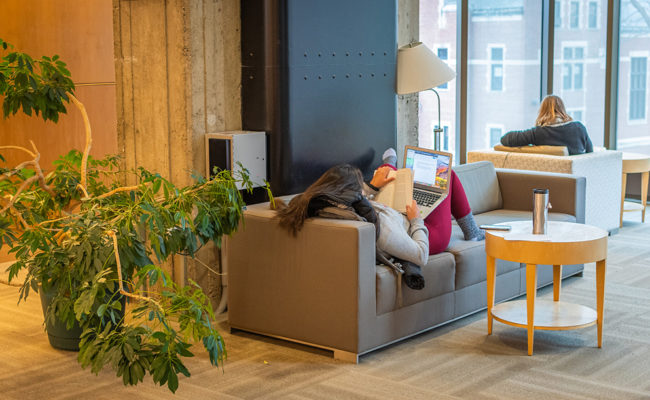 student lying on couch reading book