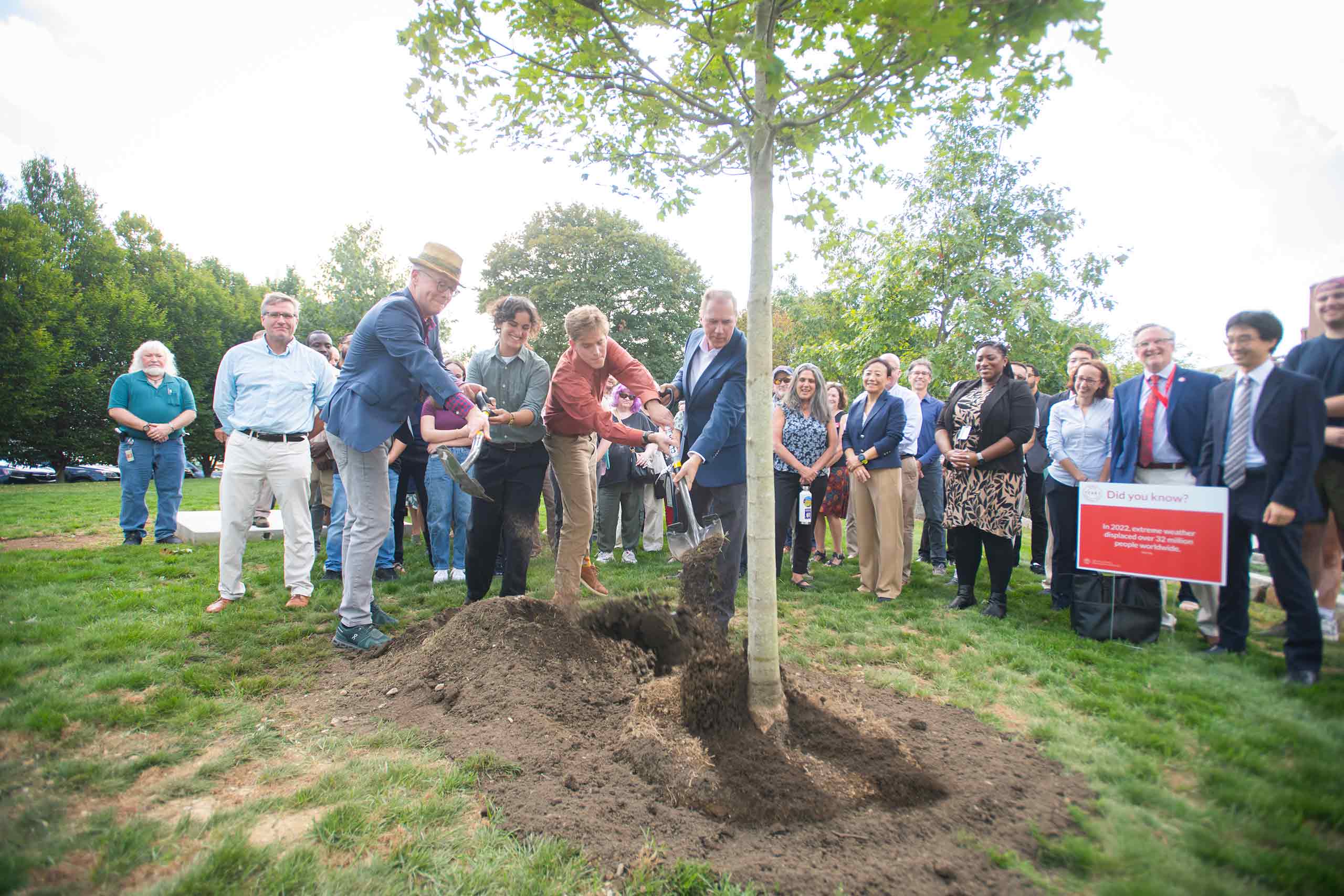 Dean Lou Leonard and President David Fithian, with Ruby Lichtman ’27 and Zach Rutherford ’27, plant a red maple by the Shaich family Alumni and Student Engagement Center at the kick-off celebration of the new School of Climate, Environment, and Society