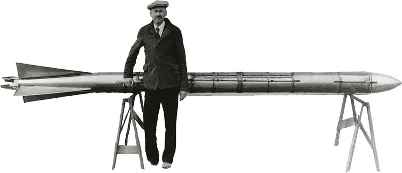 Robert H. Goddard standing in front of a rocket