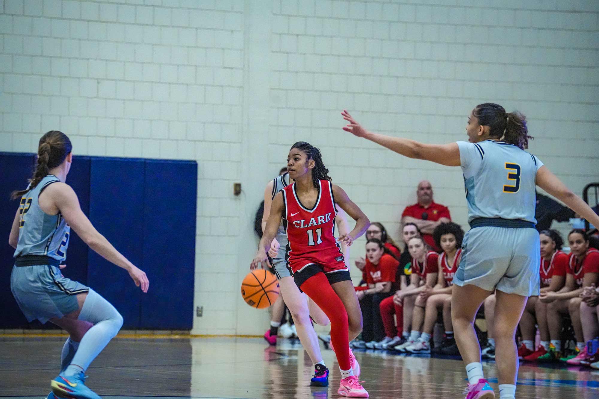 NEWMAC champion women's basketball team member dribbling the ball while surrounded by the opposing team, 2026