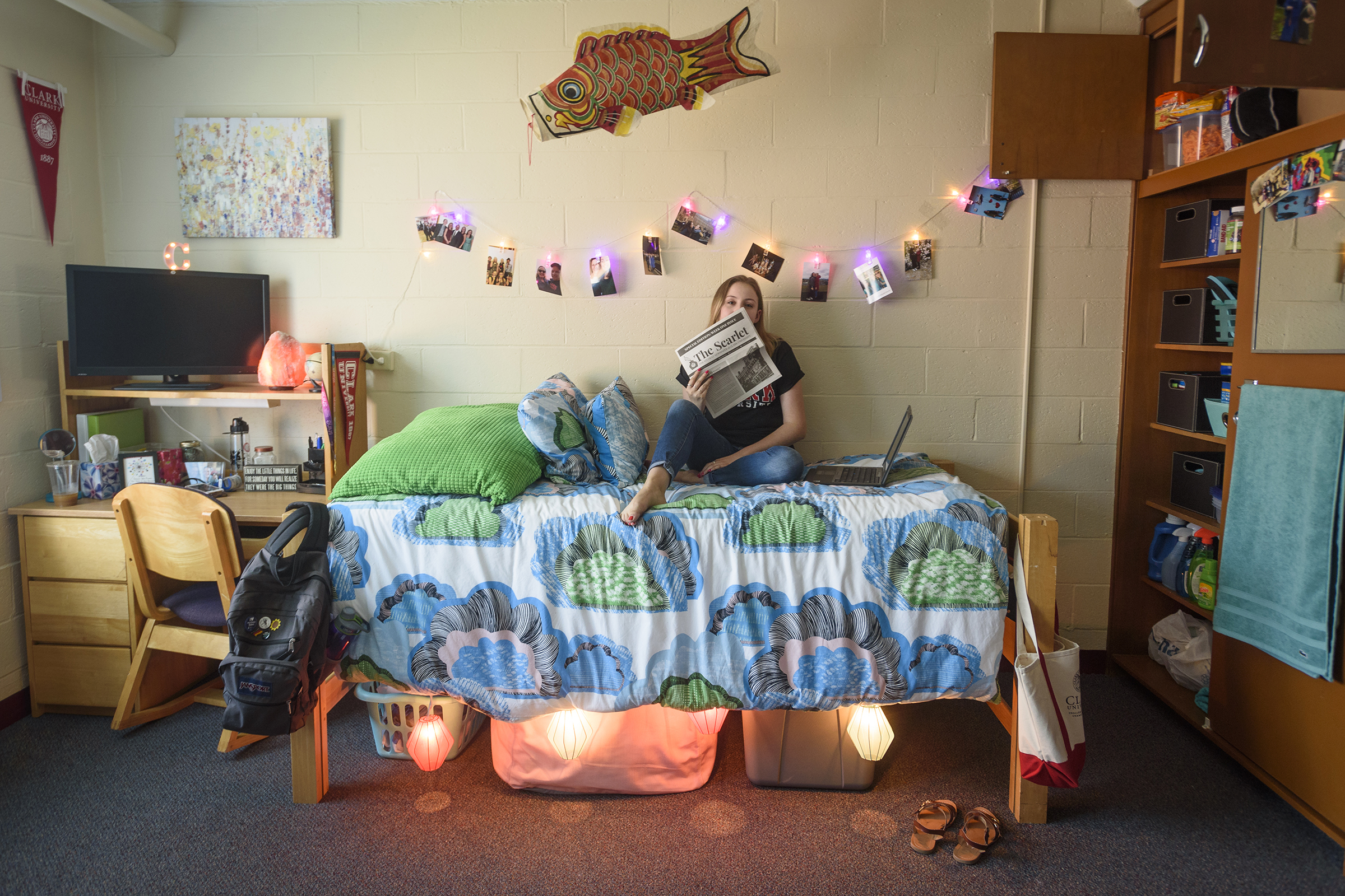 Wright Residence Hall bedroom with girl sitting on bed reading the scarlet newspaper
