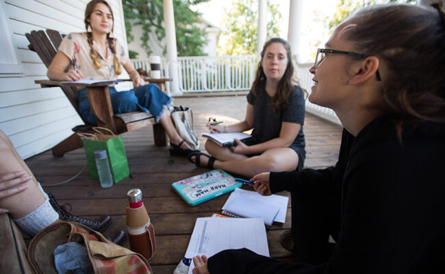 International Development, Community and Environment House - - students sitting on floor of the porch