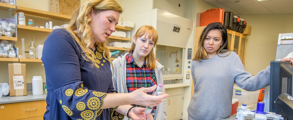 Karen Frey in lab with students looking over specimens