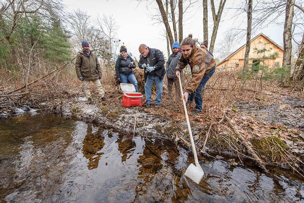 students gathering water samples on pond in winter