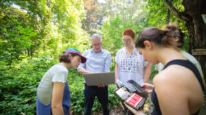 Students with Professor looking over bat sensor in fields