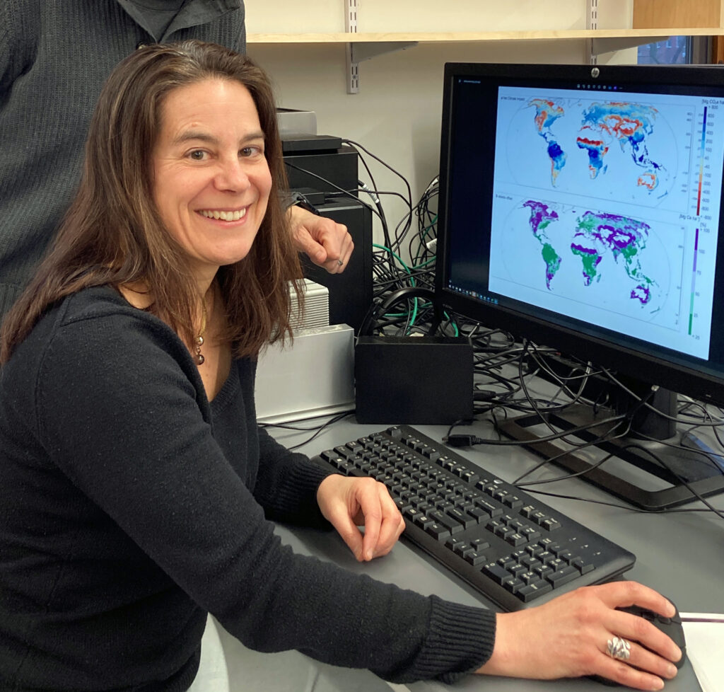 Professor Hassler behind computer looking over geo maps