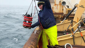 Karen Frey on ship in arctic pulling up water bucket