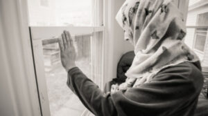 muslim woman in house looking out window