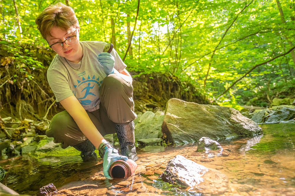 Abby Beilman gathering water from river