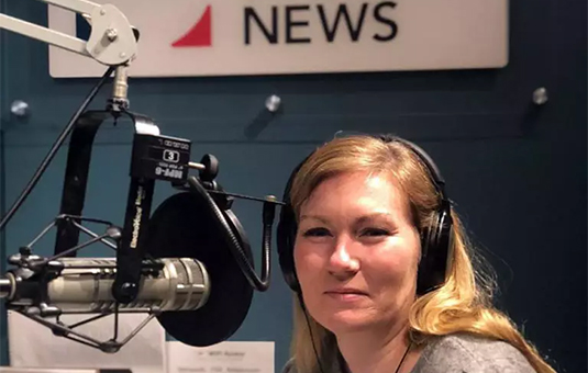 Karen Frey speaking into a mic at radio station